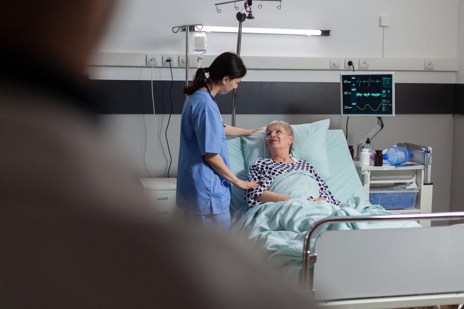 Fiendly doctor hands holding patient hand, in hospital room giving encouragement, empathy, support during medical examination. Patient breathing through oxygen mask.